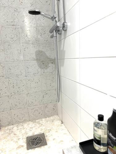 a shower in a white tiled bathroom with a drain at Uniikki keskustahuoneisto pihaterassilla, bm Garden Apartments no2, free parking in Lahti