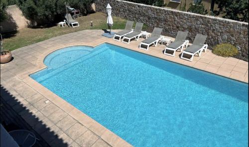une piscine avec des chaises longues et une piscine dans l'établissement Villa Bollaccia, à Aregno