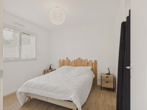 ein weißes Schlafzimmer mit einem Bett mit einem Kopfteil aus Holz in der Unterkunft Jardin clos - Maison de plain-pied pour 4 in Le Tour-du-Parc