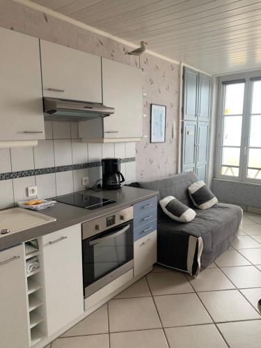- une cuisine avec un canapé au milieu d'une pièce dans l'établissement Appartement front de mer, à Grandcamp-Maisy