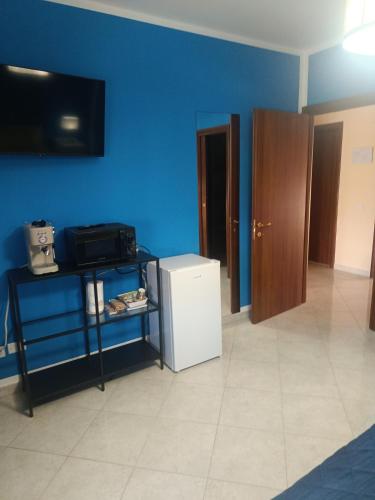 a room with a blue wall and a white refrigerator at beb Dragonara in Torremaggiore