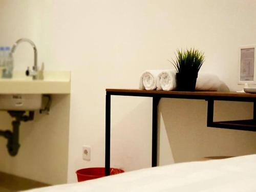 a bathroom with a sink and a table with towels at Alpine Room at TreePark City Apartement in Tangerang