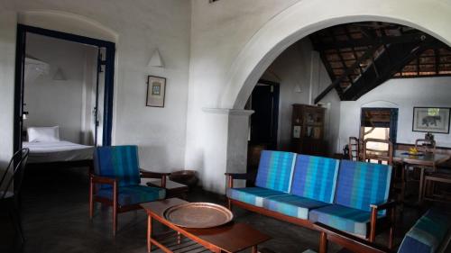 a living room with blue chairs and a bed at 15LMD Villa in Front of the Lagoon in Batticaloa