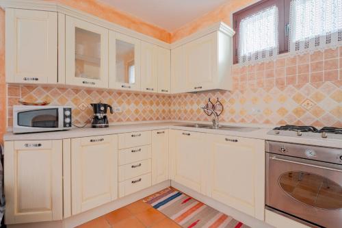 a kitchen with white cabinets and a microwave at Casa spaziosa per piu' famiglie in Bari Sardo