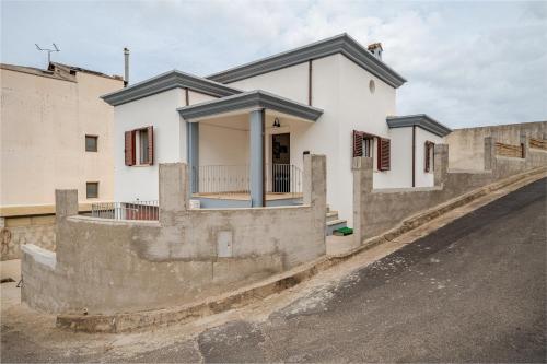 a white house with a stone wall next to a street at Casa spaziosa per piu' famiglie in Bari Sardo
