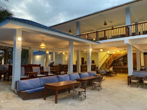 a large patio with a blue couch and tables at Summer Beach Paje in Paje
