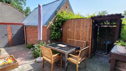 a patio with a table and chairs and a fence at Ferienhaus Dörpblick in Krummhörn