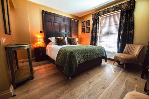 a bedroom with a bed and a chair and a window at RHUBARB at Drapers Hall in Shrewsbury
