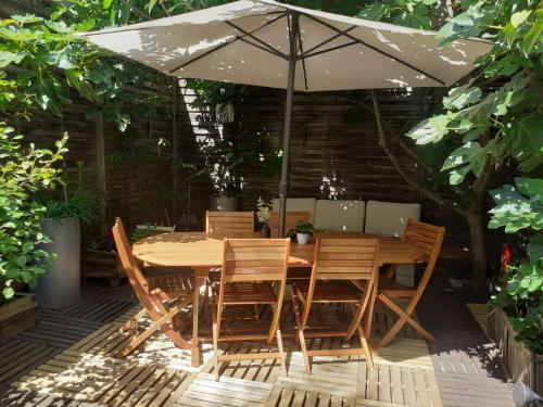 une table et des chaises en bois sous un parasol dans l'établissement Le Nid Bord De La Loire, à Orléans