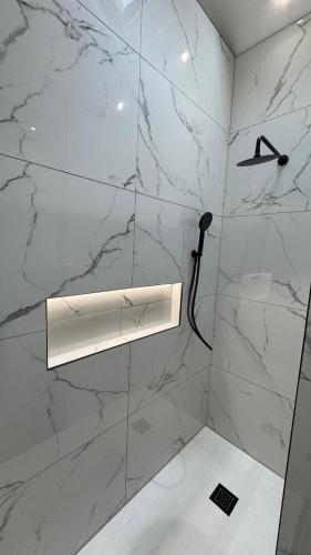 a bathroom with white marble walls and a light fixture at Ultra-Central Loft Penthouse Sky Sports & Movies in Leeds
