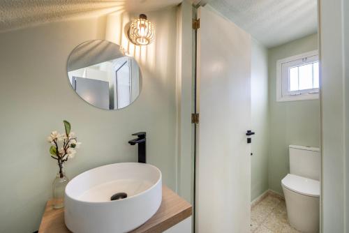 La salle de bains est pourvue d'un grand lavabo blanc et d'un miroir. dans l'établissement Laranca Oneiro Seaside Villa, à Perivólia