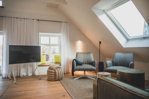 a living room with two chairs and a flat screen tv at Appartements Brigg & Schoner in Neuharlingersiel