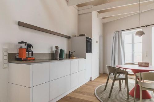 a kitchen with white cabinets and a red table at Appartements Brigg & Schoner in Neuharlingersiel