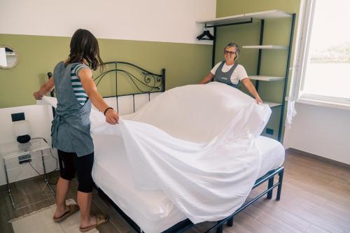 two women standing around a bed in a room at Agriturismo Le Marognole in Colà di Lazise