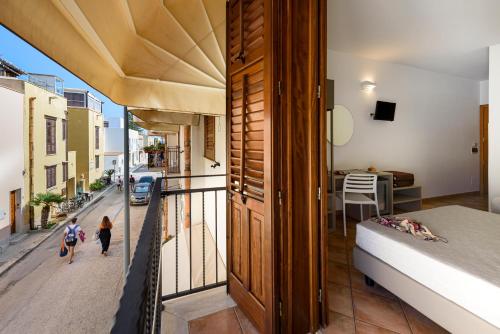 a room with a balcony with a bed and a street at Sun Garden in San Vito lo Capo