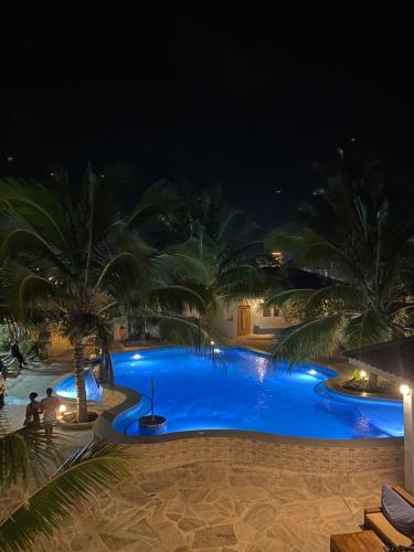 a swimming pool at night with palm trees at Summer Beach Paje in Paje