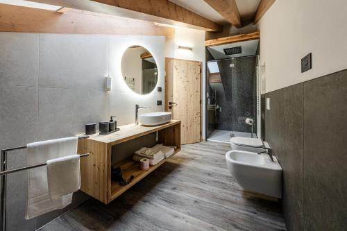a bathroom with a sink and a toilet and a mirror at Villetta Val Di Sole in Commezzadura