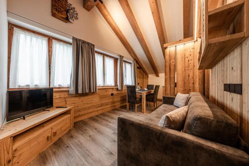 a living room with a couch and a tv at Villetta Val Di Sole in Commezzadura