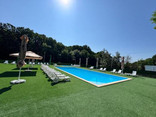 a swimming pool with lawn chairs and umbrellas at Hotel Doi Haiduci in Orhei