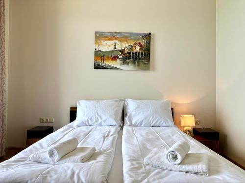 a bedroom with a bed with white sheets and towels at Cosher - Gardenia Palace Apt 11 in Pomorie