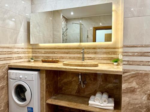 a bathroom with a sink and a washing machine at Cosher - Gardenia Palace Apt 11 in Pomorie