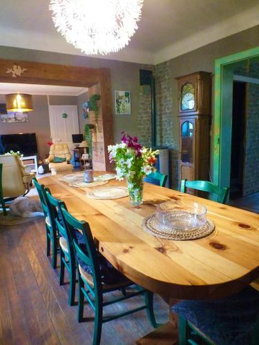 une grande table en bois avec des chaises et un vase de fleurs dans l'établissement Domaine L'Insolite KOSI, à Cirey-sur-Vezouse