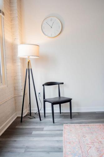 a lamp and a chair and a clock on a wall at 3BR CozySuites at The Block Pool Table and Arcade in Indianapolis