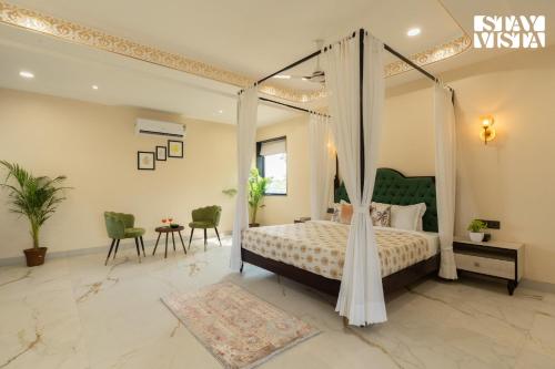 a bedroom with a canopy bed and a table and chairs at StayVista at Eleganza Villas & Resort, Jaipur in Jaipur