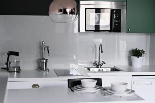 a white kitchen with a sink and a microwave at Emerald Mokotowska 59 in Warsaw
