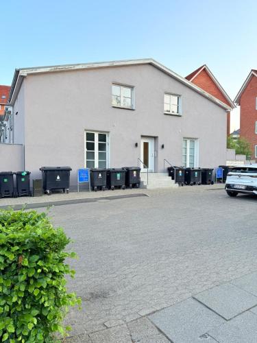 a white building with trash cans in a parking lot at Spacious Pearl in Viborg Centre in Viborg