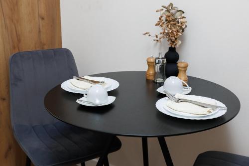 a black table with plates and utensils on it at Apartment in Chișinău, near the Airport in Chişinău