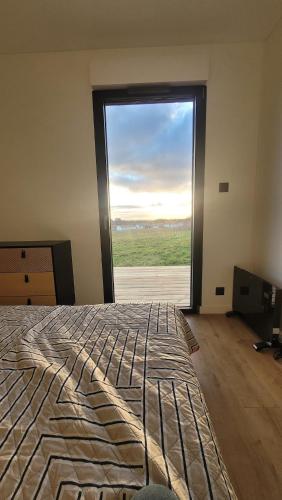 une chambre avec un lit et une grande fenêtre dans l'établissement La Box des Oiseaux, à Gamarde-les-Bains