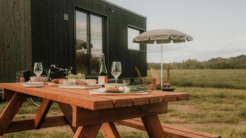 - une table de pique-nique avec des verres à vin et de la nourriture dans l'établissement Parcel Tiny House Ty Pois 1, près de la pointe de la torche, à Plonéour-Lanvern