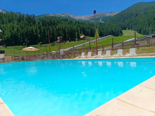 une grande piscine avec des chaises et des montagnes en arrière-plan dans l'établissement Les Valerianes - Vue Montagne, aux Orres