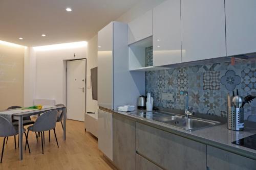 a kitchen with a sink and a table with chairs at PALAZZO NOVA luxury apartments in Acerra
