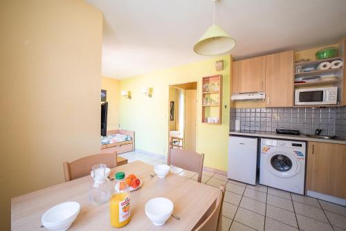 une cuisine avec une table en bois et une cuisine avec un lave-linge dans l'établissement Le Cap et la Mer - Vue Mer, à Cerbère