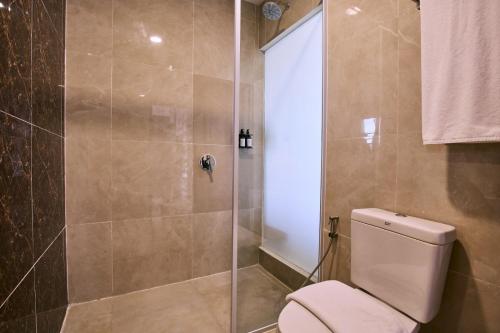 a bathroom with a toilet and a glass shower at Horison Ultima Sayaga Cibinong 