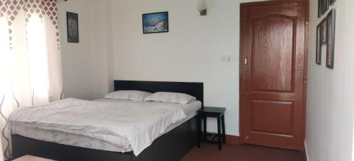 a bedroom with a bed and a wooden door at Amu Ghumounte Stay in Pātan