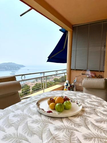 une assiette de fruits sur une table avec un balcon dans l'établissement Elégance d'époque - Vue Panoramique Mer, à Villefranche-sur-Mer