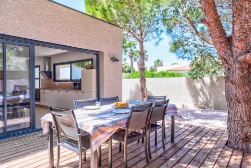 une table et des chaises sur une terrasse avec une maison dans l'établissement Villa Louise, à Lapalme