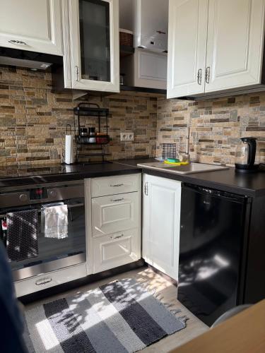 a kitchen with white cabinets and a black dishwasher at Apartament Staromiejski in Olsztyn