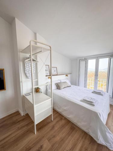 a white bedroom with a white bed and a shelf at Loft Deluxe Torre del Pan in Olvera