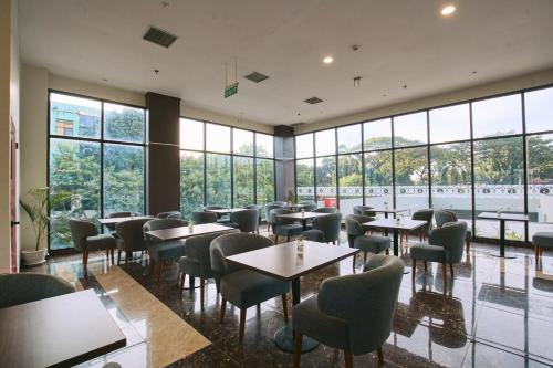 a restaurant with tables and chairs and large windows at Horison Ultima Sayaga Cibinong 