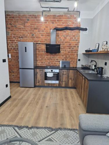 a kitchen with a white refrigerator and a brick wall at Apartamenty MILANHOUSE in Gołdap