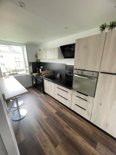 Il comprend une cuisine avec des appareils en acier inoxydable et du parquet. dans l'établissement 85m2 Neuf, Lumineux et Spacieux en Centre-ville, à Saint Lo