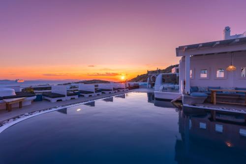 a sunset over a body of water with buildings at Flaskos Luxury Suites in Agios Stefanos