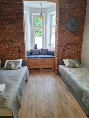 a room with two beds and a brick wall at Apartamenty MILANHOUSE in Gołdap
