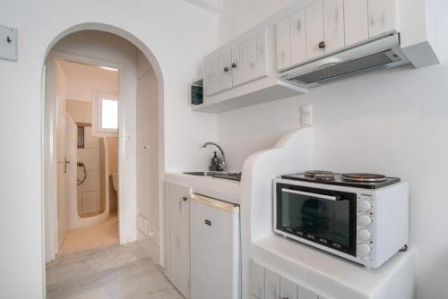 a kitchen with white cabinets and a microwave at Maroulis Studios Naxos in Mikri Vigla