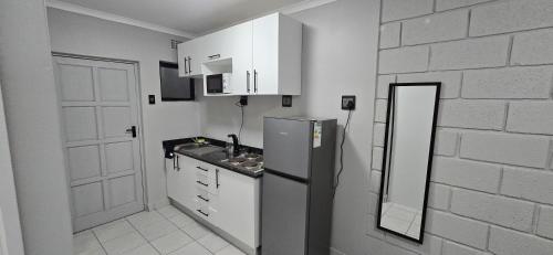 cocina con nevera y pared de ladrillo blanco en Grace Villas 35, en East London