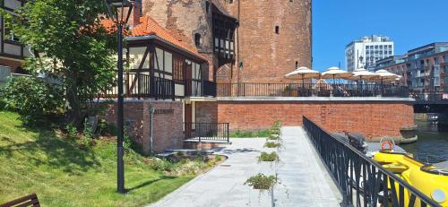 a brick building with a balcony with tables and umbrellas at Jacht AMBER in Gdańsk